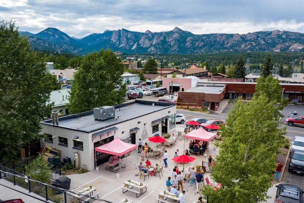 Aerial view of Avant Garde Aleworks patio with red umbrellas and Rocky Mountain views