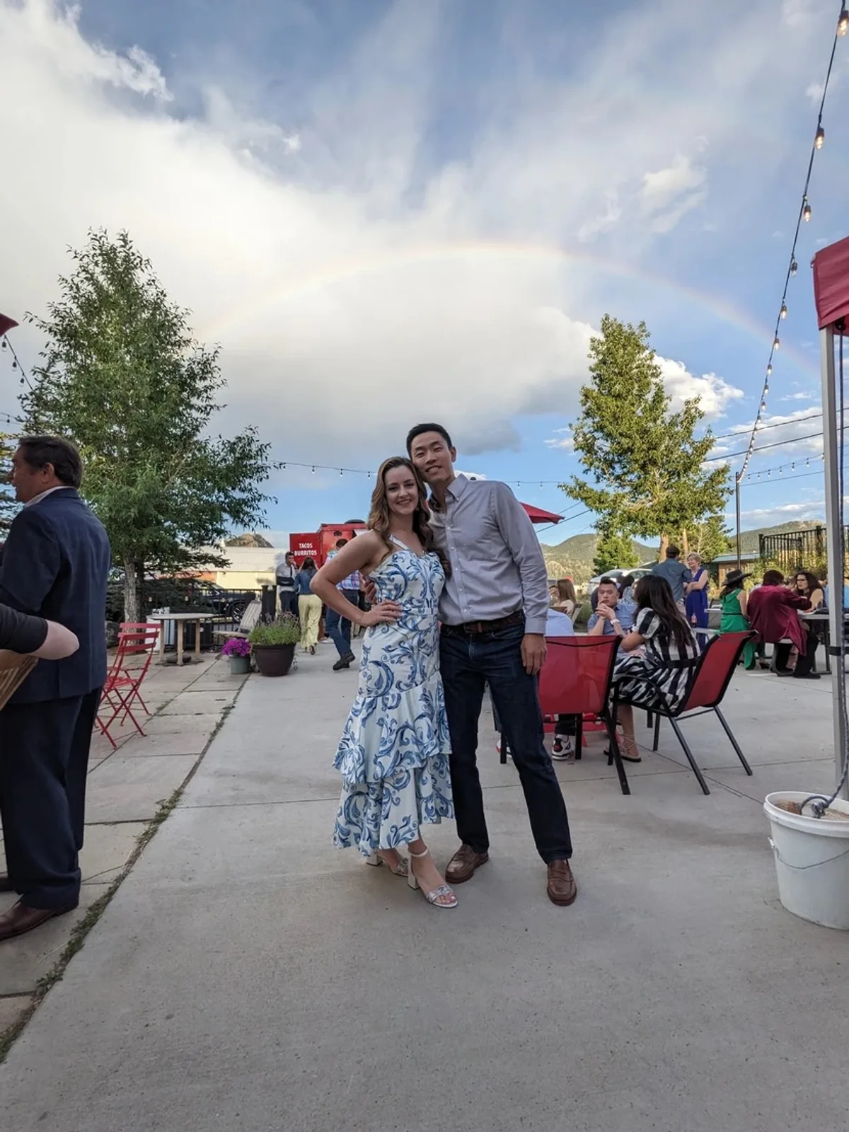 Guests gathering at Avant Garde Aleworks with a rainbow over the patio
